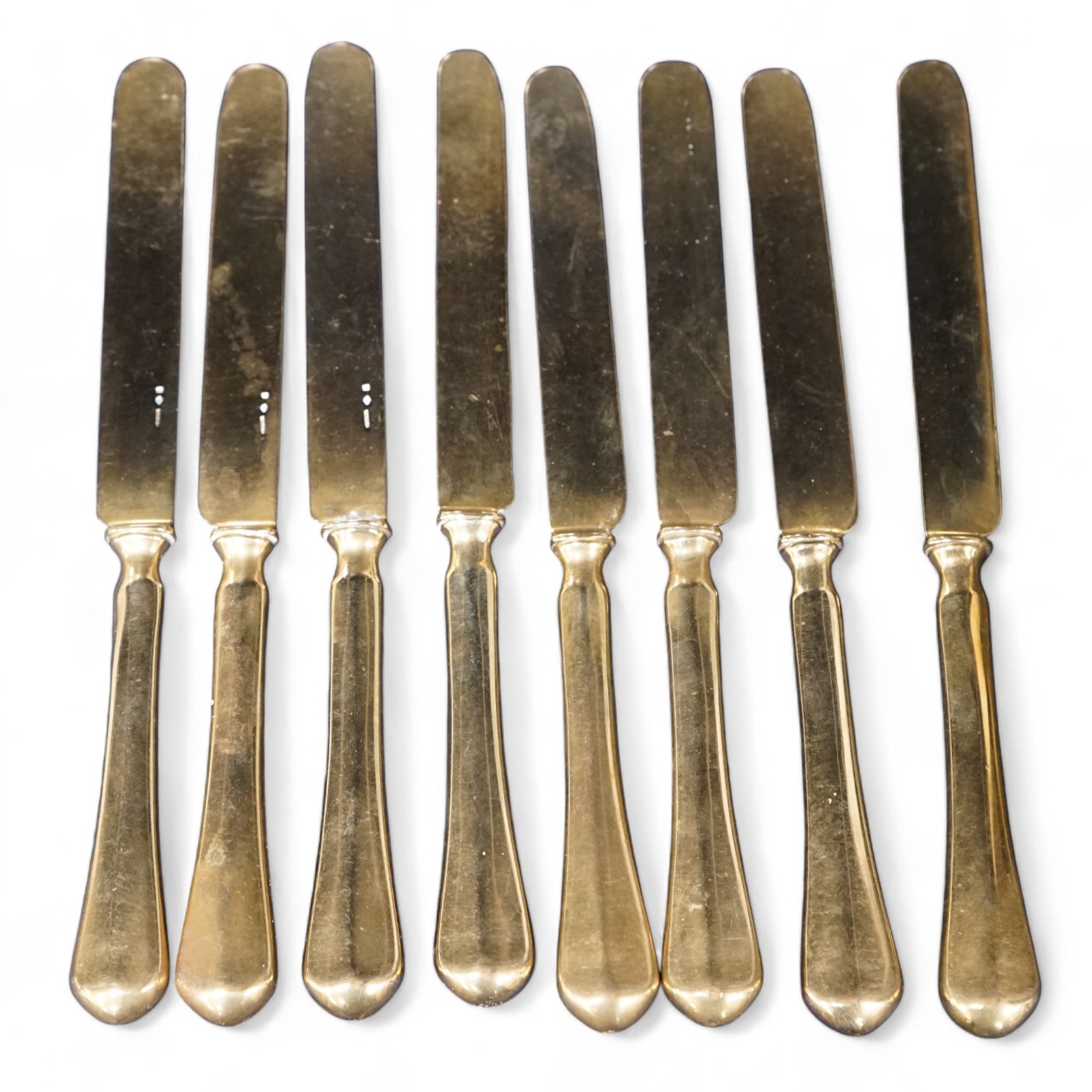 A set of eight French gilt plated dessert knives, 20cm. Condition- fair to good, some nicks and scratches